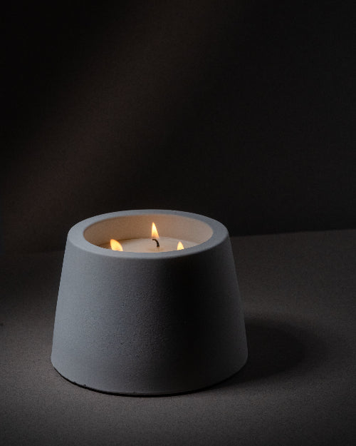
                  
                    Gray candle holder with a lit candle on a dark background
                  
                
